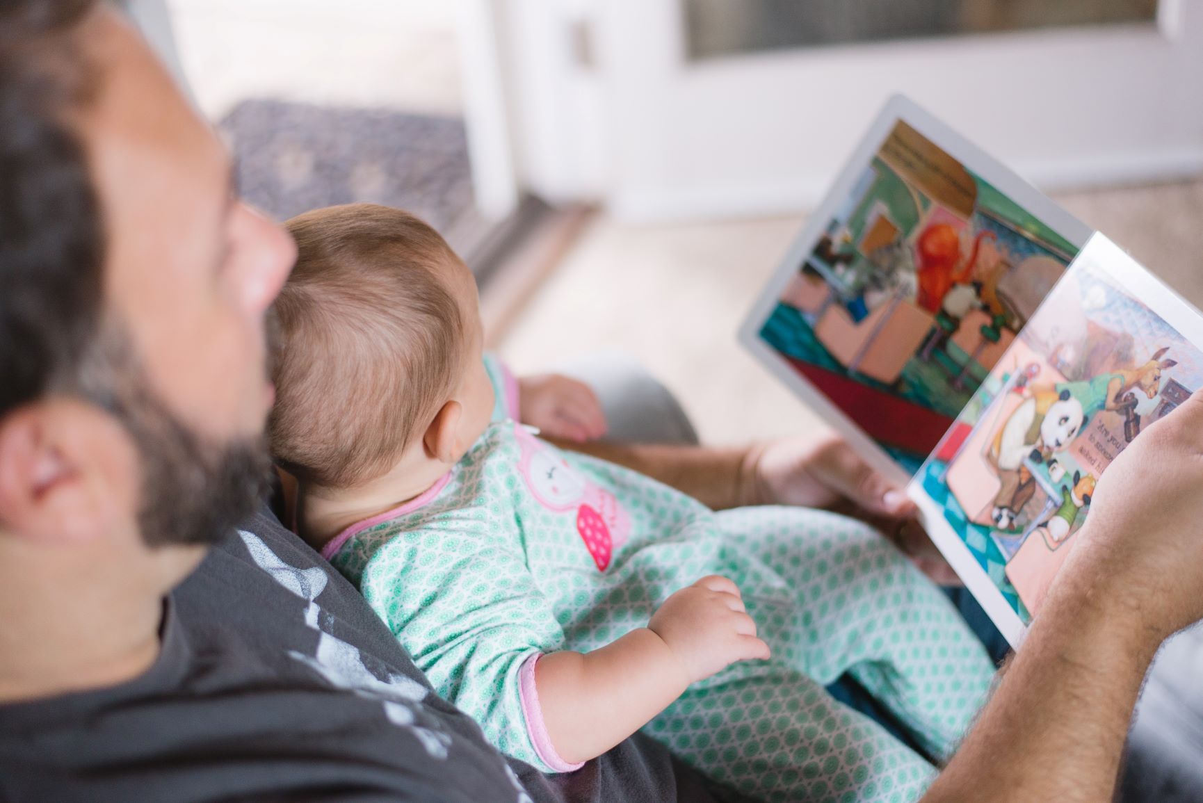 father reading a board book to an infant
